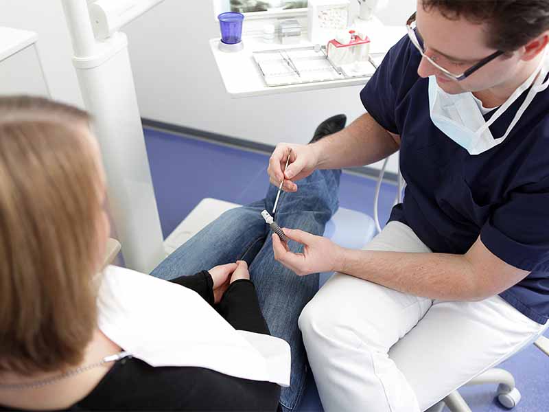Zahnarzt erklärt Patientin ein Zahnimplantat in Lübeck